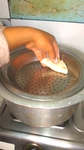 फरा को स्टीम करने के लिए बड़े बर्तन में रखते हुए