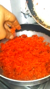 Grated carrots cooking in a pan until steam appears