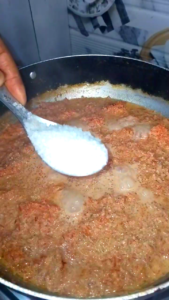 Adding sugar while cooking Gajar Ka Halwa in a pan