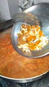 Adding dry fruits to Gajar Ka Halwa before serving