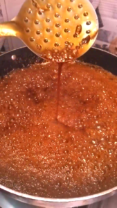 Testing jaggery syrup consistency in water for til chikki