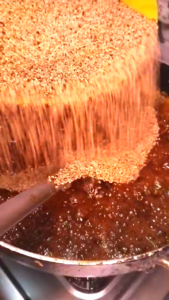 Mixing roasted sesame seeds into melted jaggery for til chikki