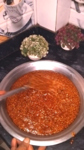 Spreading til chikki mixture evenly with spoon or rolling pin