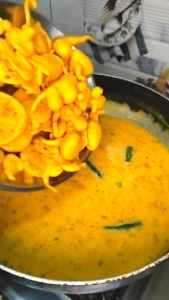 adding pakoras to simmering kadhi pakora curry soft besan fritters
