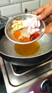 Adding Garlic, Onion, Hing, Fenugreek Seeds and Dry Red Chilies to Hot Mustard Oil